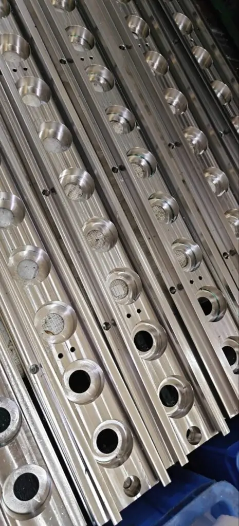 Machined metal plates with rows of drilled and recessed holes